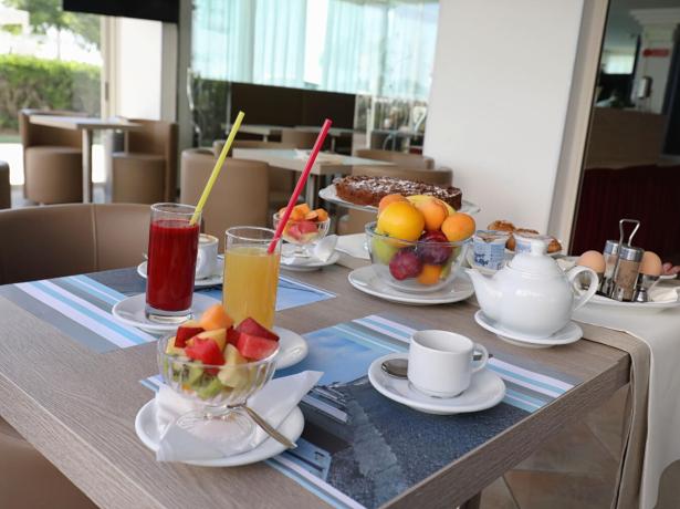 Colazione con succhi, frutta, torta e tè in un ambiente moderno.