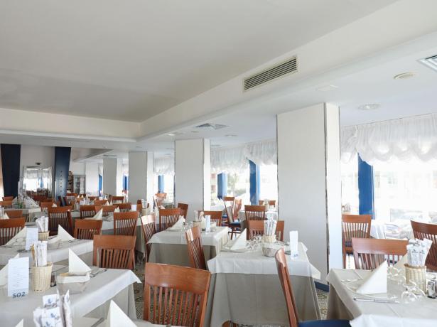 Ristorante elegante con tavoli apparecchiati e sedie in legno.