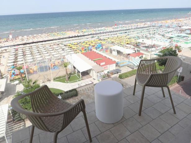Vista mare con sedie e tavolino su un balcone.